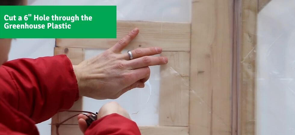 cutting a hole in the greenhouse plastic